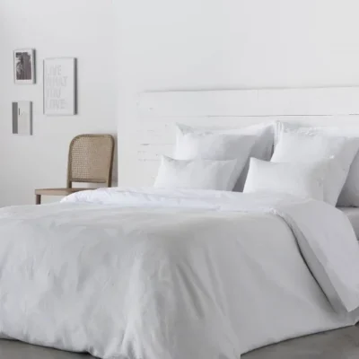 Housse de couette ANGELO en satin 300 fils 100% coton, mise en valeur sur un lit moderne.