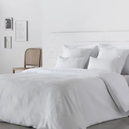 Housse de couette ANGELO en satin 300 fils 100% coton, mise en valeur sur un lit moderne.